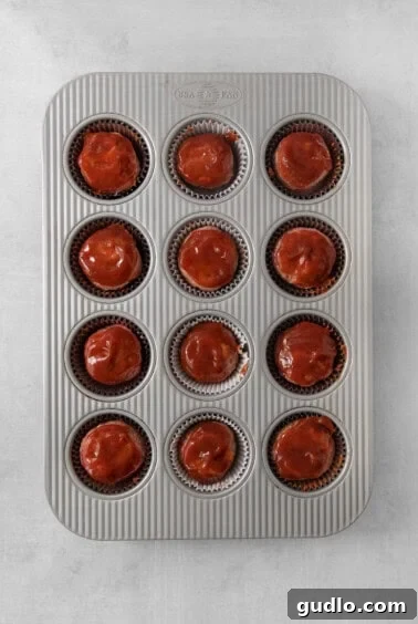 Individual Meatloaf Cups 6 A muffin tin filled with meatloaf muffins, freshly glazed and ready for the oven.