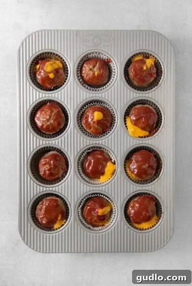 Individual Meatloaf Cups 7 Baked meatloaf muffins with melted cheese, cooling in a muffin tin.
