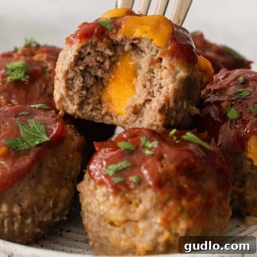 Cheesy meatloaf muffins on a plate with a fork.