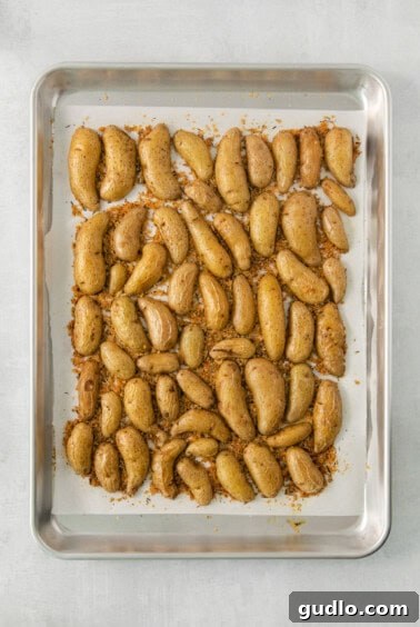Golden Parmesan Potatoes 7 Golden brown roasted potato halves on a baking sheet, fresh out of the oven.