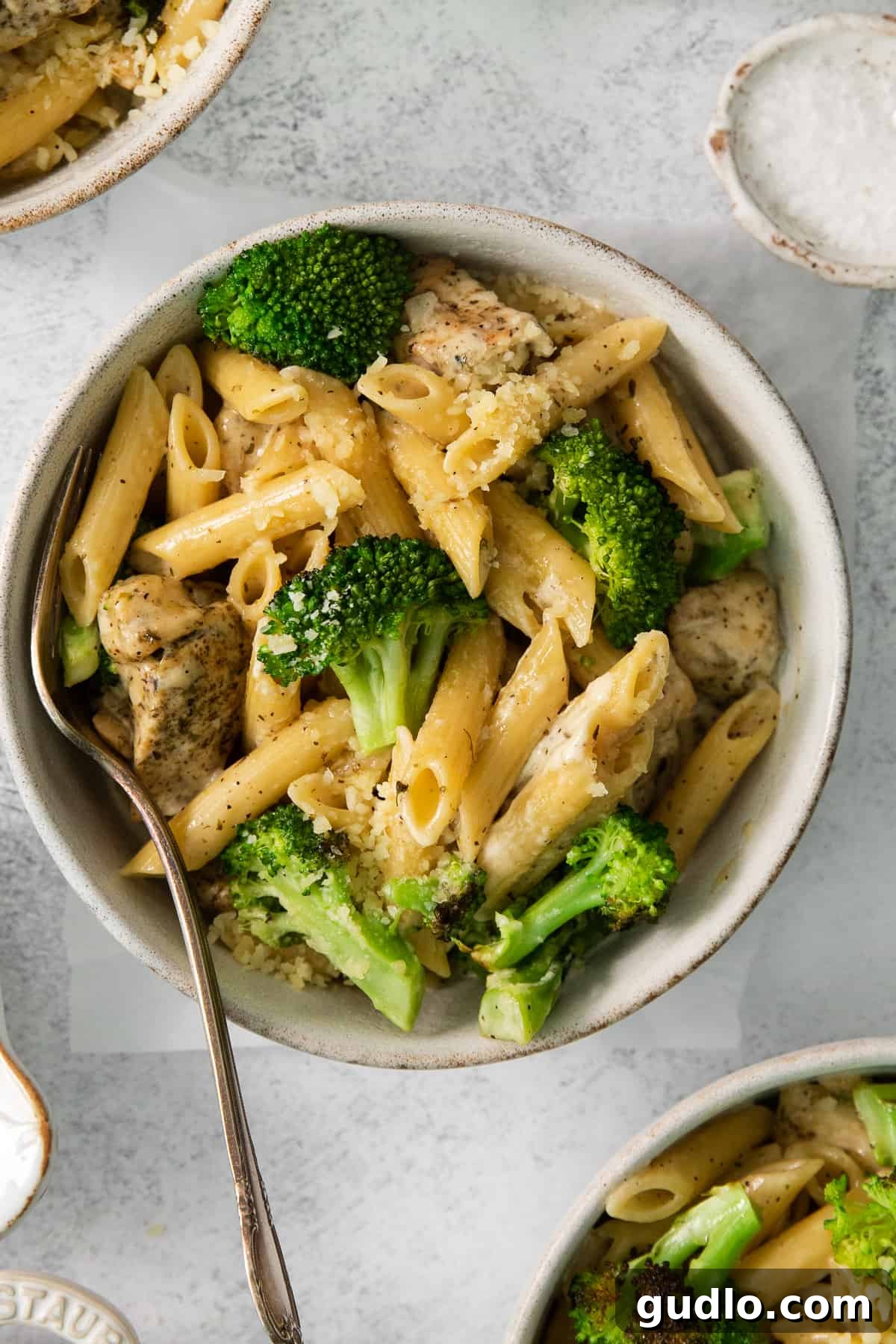 A beautifully plated bowl of creamy chicken broccoli alfredo pasta, garnished with fresh parsley.