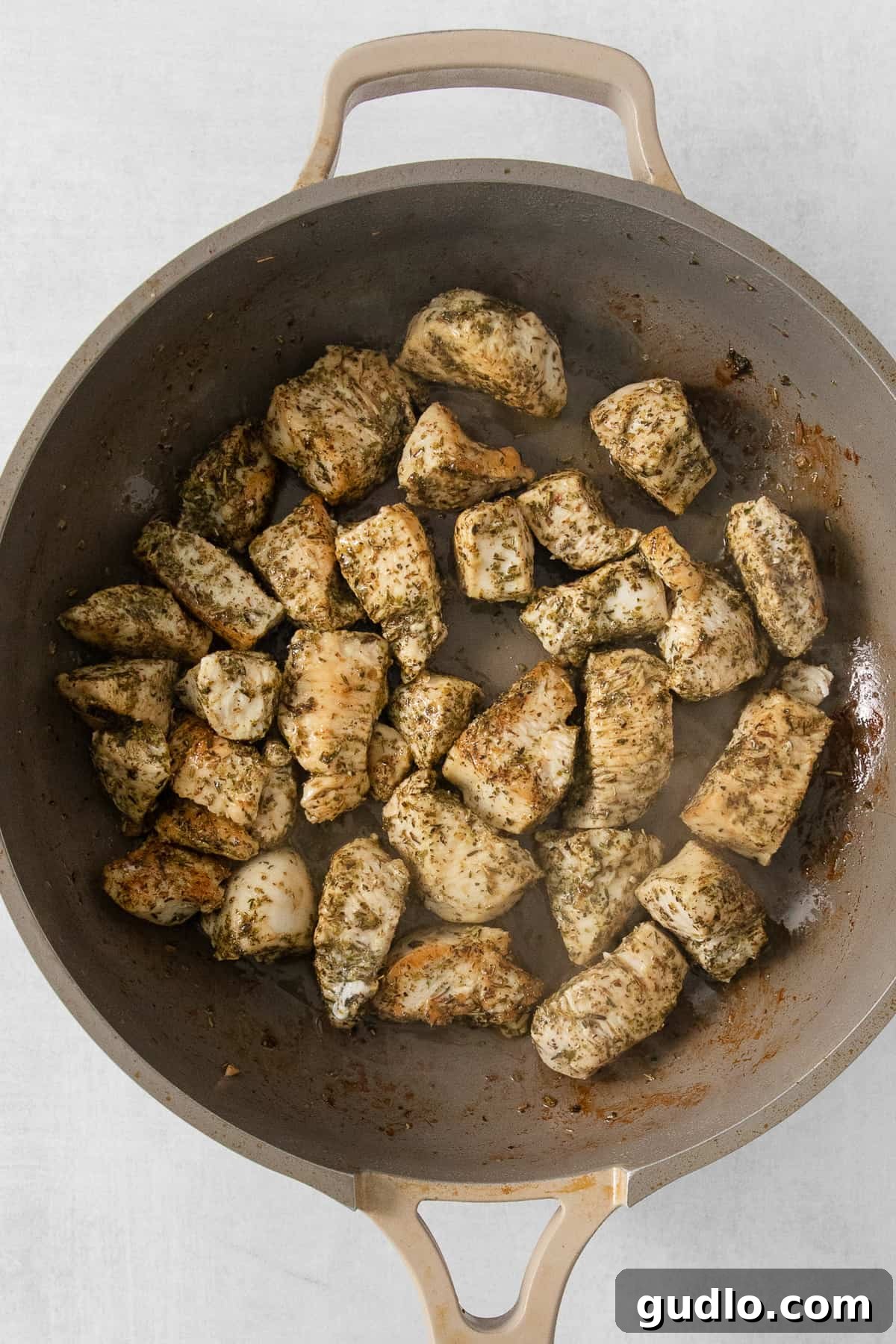 Sautéed chicken pieces glistening in a skillet, perfectly browned and ready for the creamy sauce.