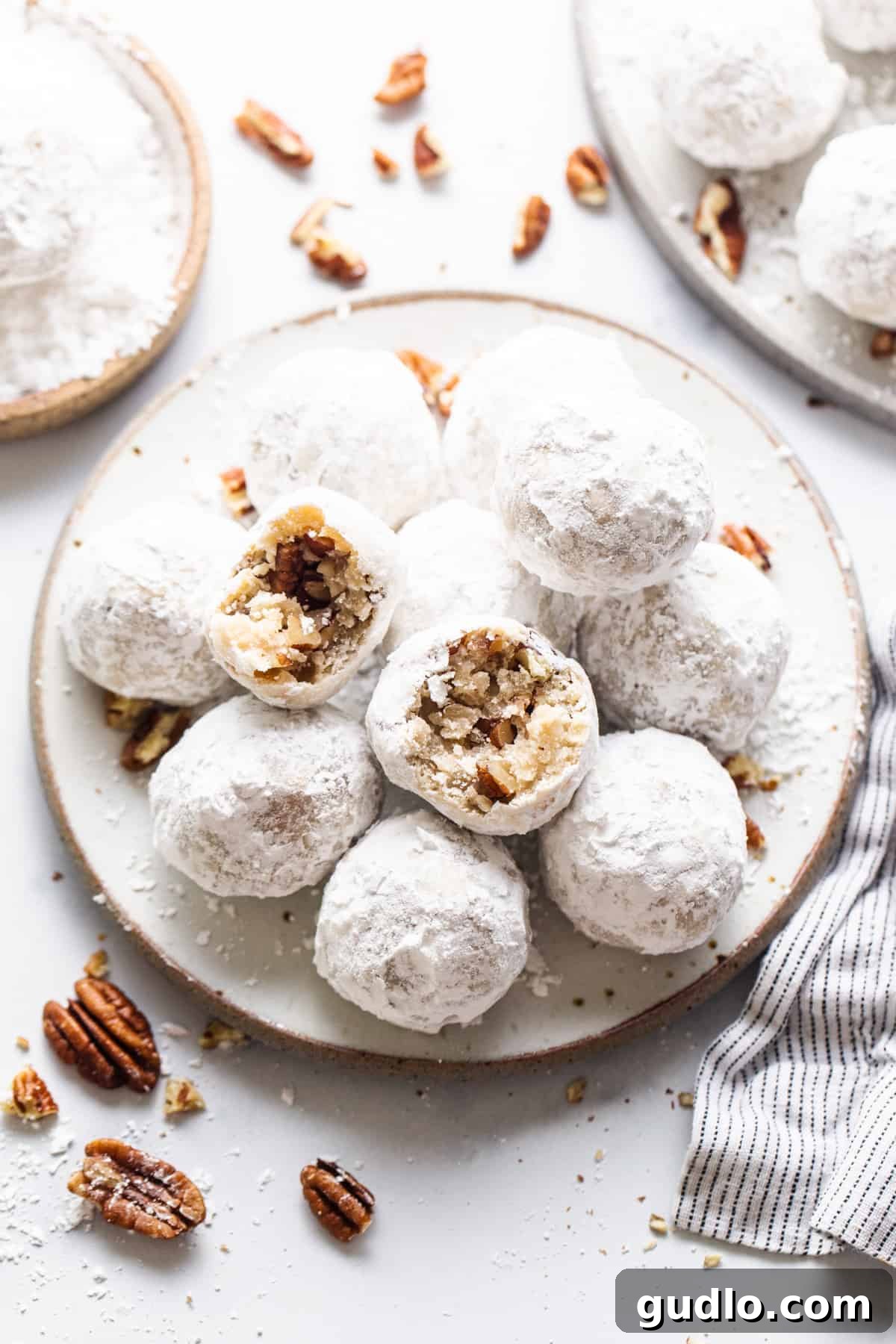 Powdered sugar cookies with ground pecans on a white ceramic plate, ready for the holidays.
