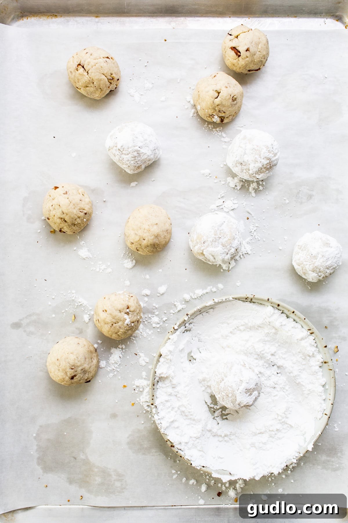 Delicate almond cookies generously dusted with powdered sugar, arranged on a baking sheet.