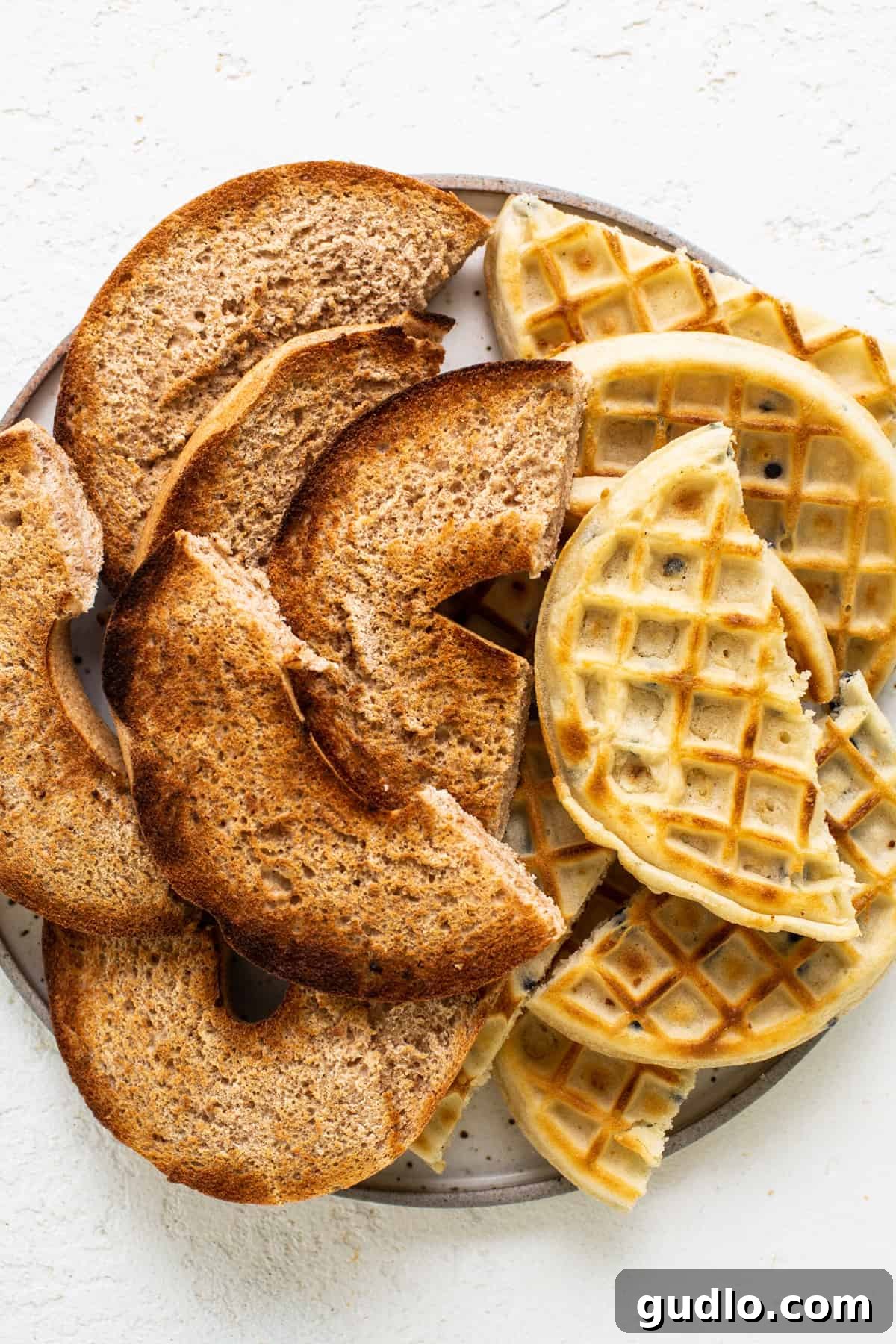 Crispy, golden waffles artfully arranged on a pristine white plate, waiting to be drizzled with syrup and served as a sweet component on the breakfast charcuterie board.