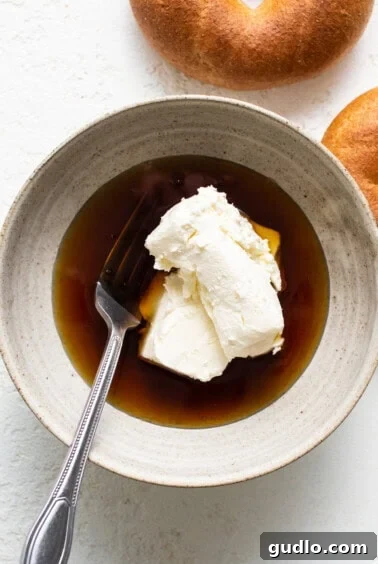 A small bowl of creamy maple cream cheese spread, ready for serving alongside bagels, highlighting a key sweet and savory element of the board.