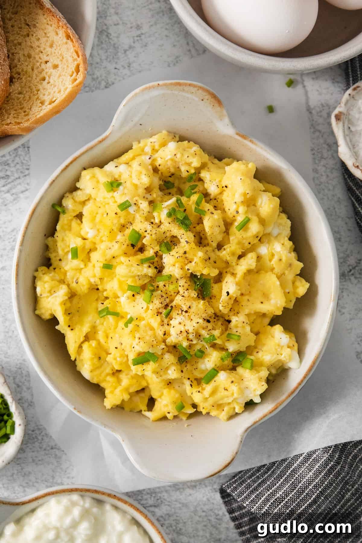 Scrambled eggs with chives and bread on a table.