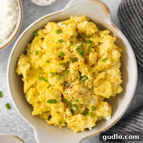 Scrambled eggs in a bowl with chives and sour cream.