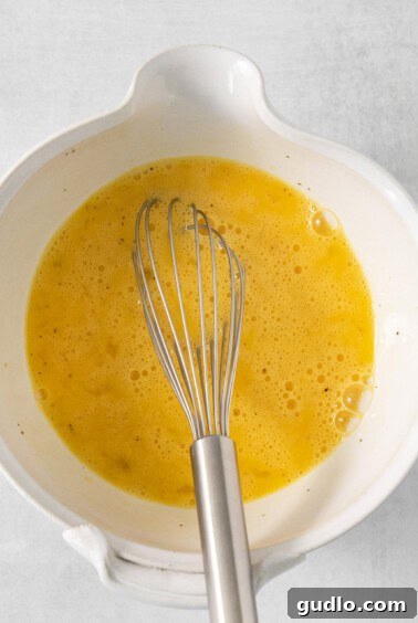A white bowl with a whisk in it.