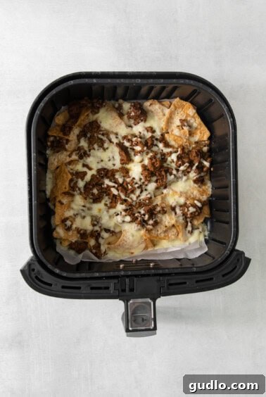 No-Fuss Air Fryer Nachos 11 An air fryer basket showcasing a fresh batch of cheesy nachos, hot and ready to be topped.