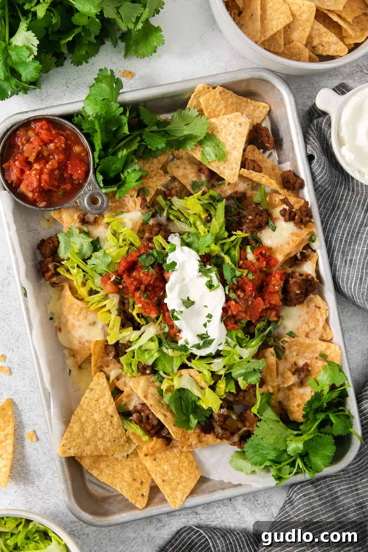 No-Fuss Air Fryer Nachos 6 A vibrant tray of Mexican nachos, generously topped with fresh sour cream, creamy guacamole, and sprinkled with fresh cilantro.