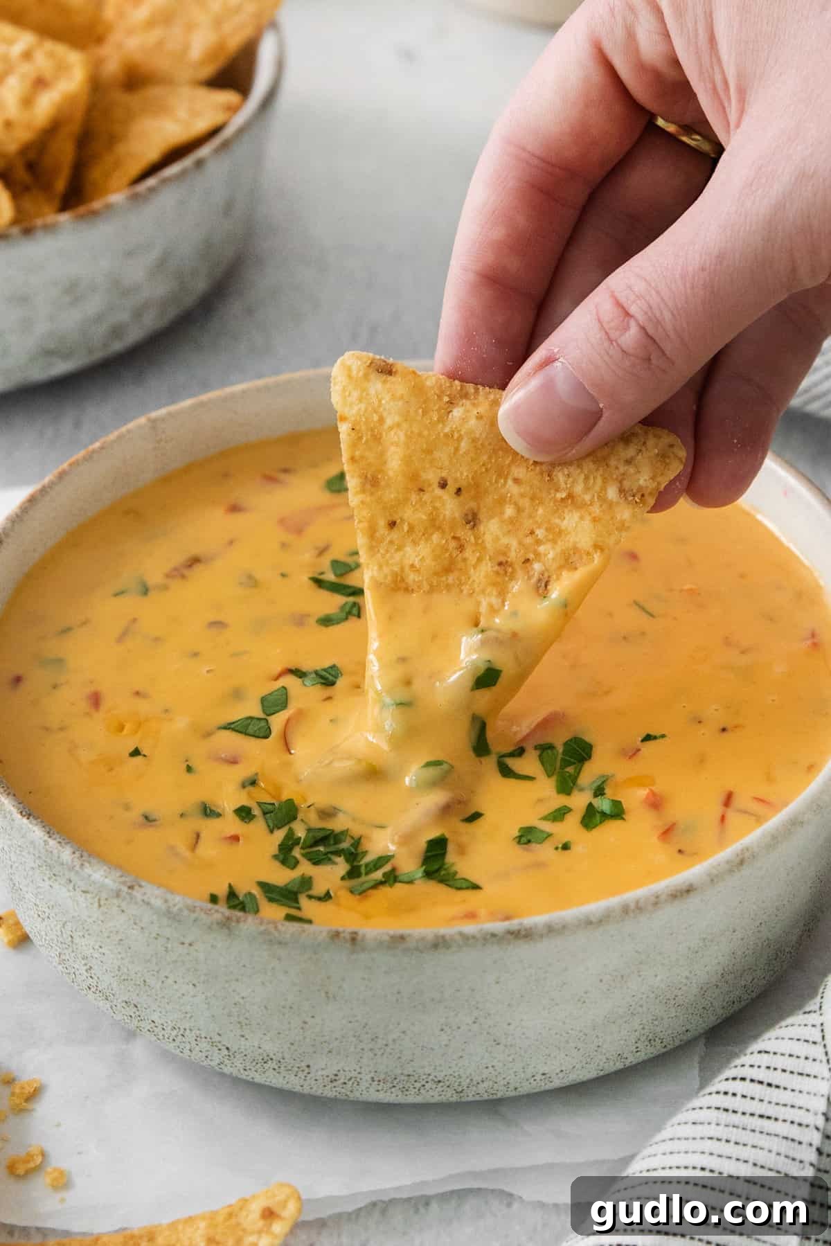 Quick Velveeta Queso: Ready in 15 Minutes 6 A person dipping a tortilla chip into a bowl of cheese dip.