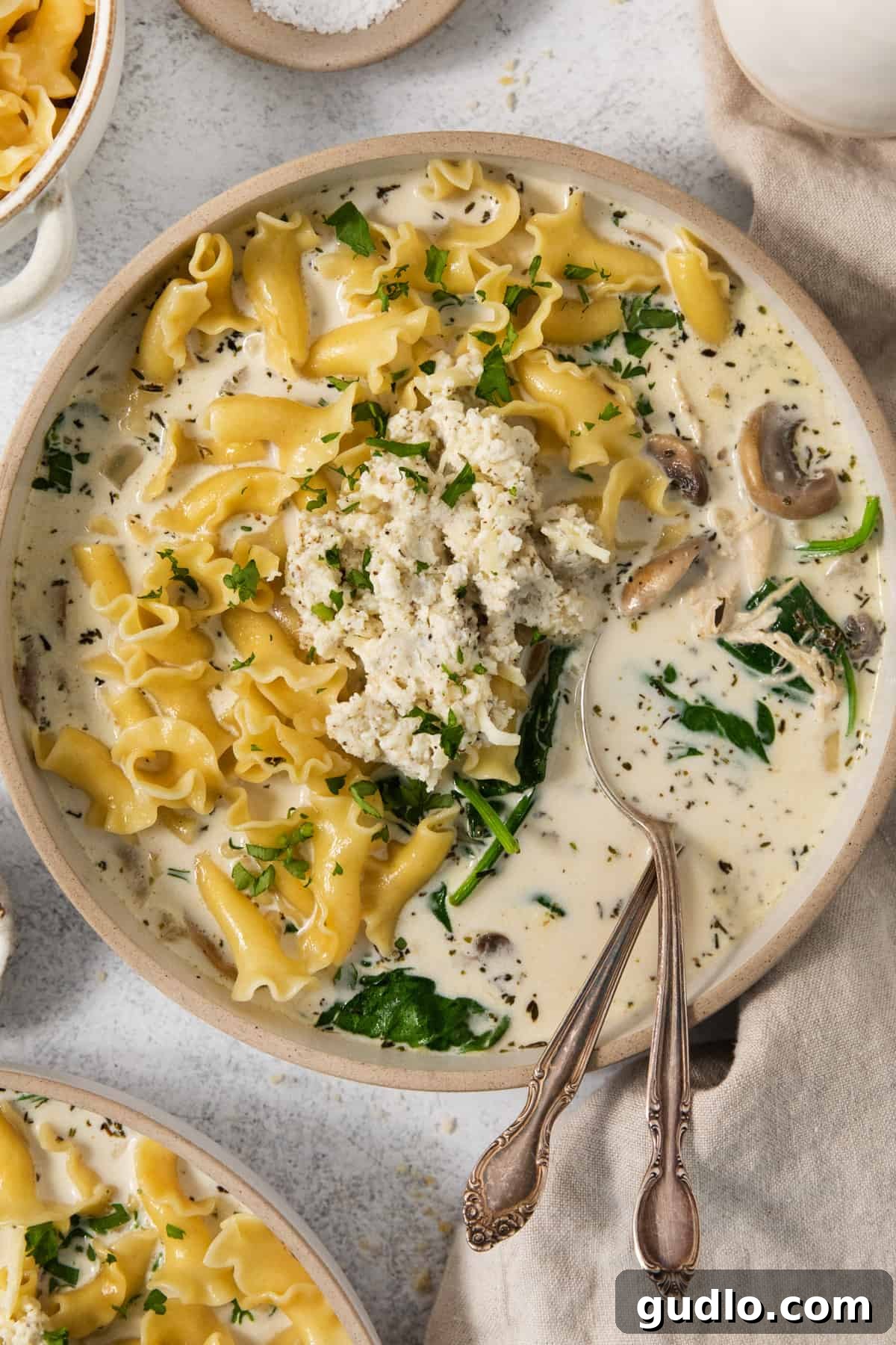 Hearty Cream Lasagna Soup 2 A bowl of creamy white lasagna soup with spinach and mushrooms, ready to be enjoyed.