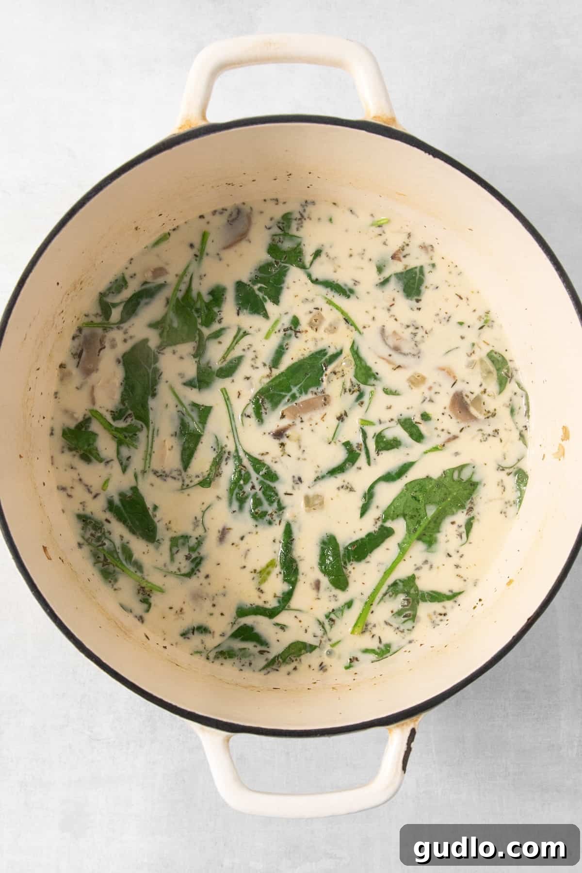 Hearty Cream Lasagna Soup 3 A pot of creamy white lasagna soup simmering with spinach and mushrooms in a Dutch oven.
