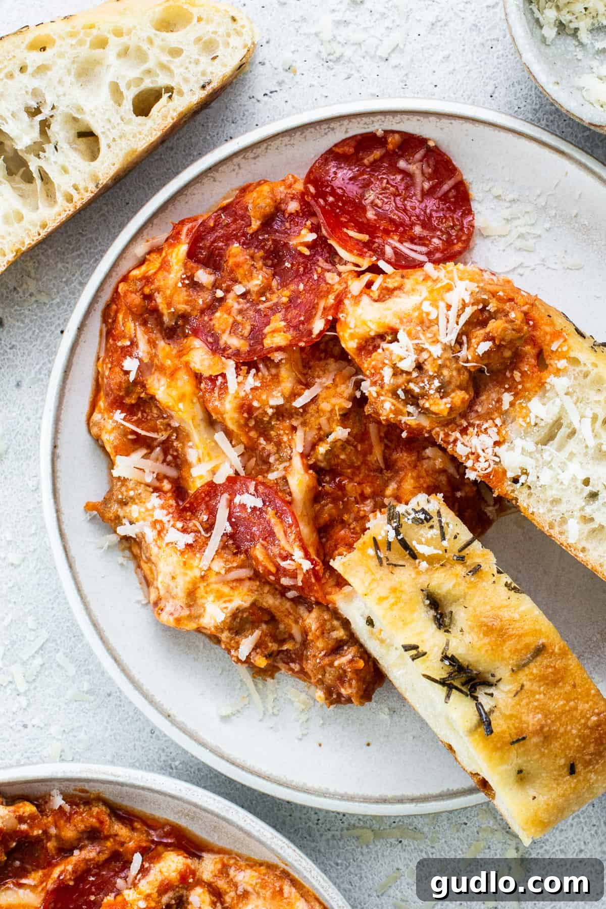 Baked Cheesy Pizza Dip with Toasted Focaccia 3 A close-up of cheesy pizza dip with pepperoni slices.