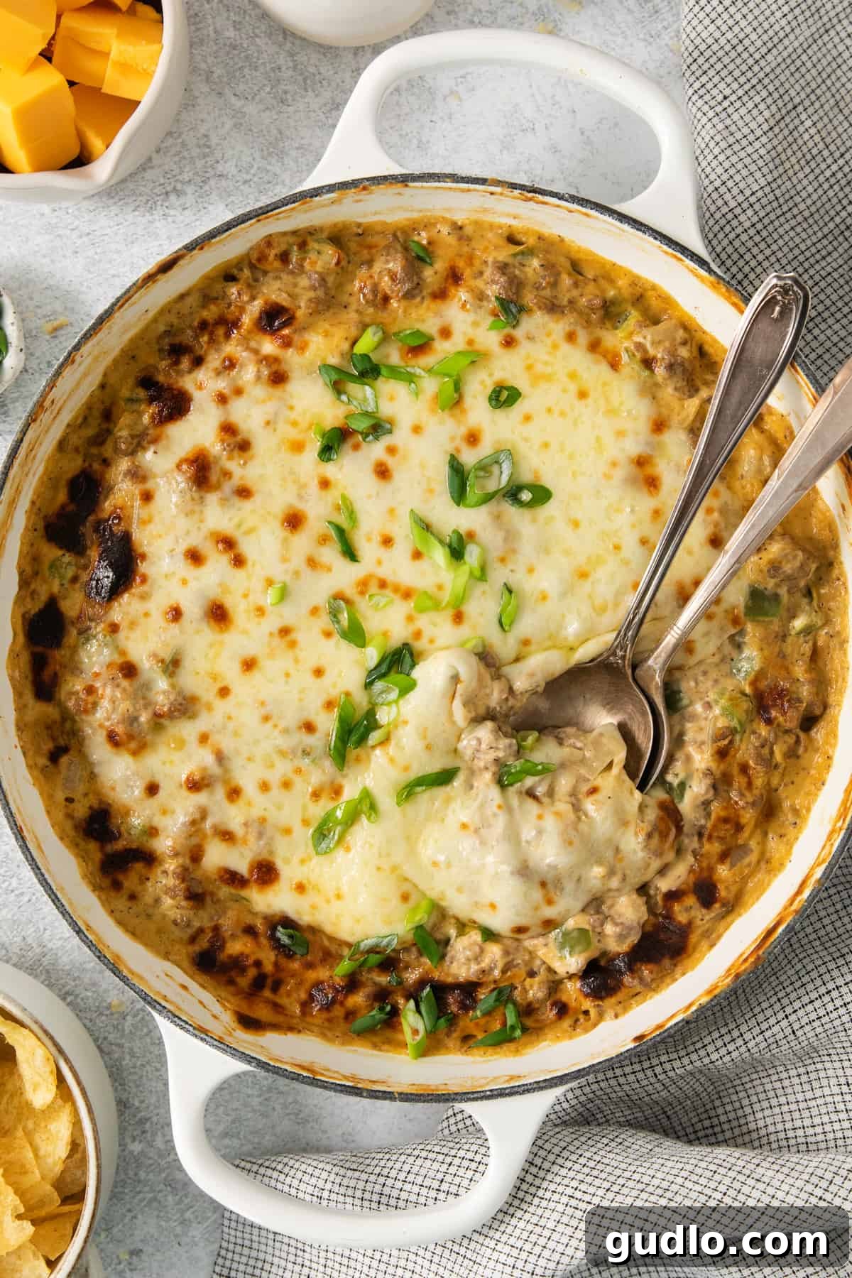 Decadent Philly Cheesesteak Dip 2 A bubbling, cheesy Philly Cheesesteak Dip in a white baking dish, ready to be served with a spoon.