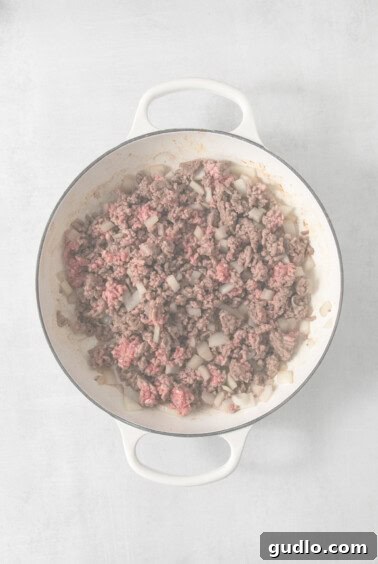 Decadent Philly Cheesesteak Dip 8 Ground beef and onions sautéing in a skillet.