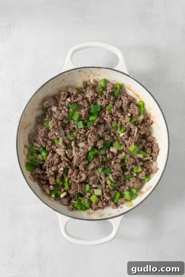 Decadent Philly Cheesesteak Dip 9 Seasoned ground beef and vegetables in a pan.