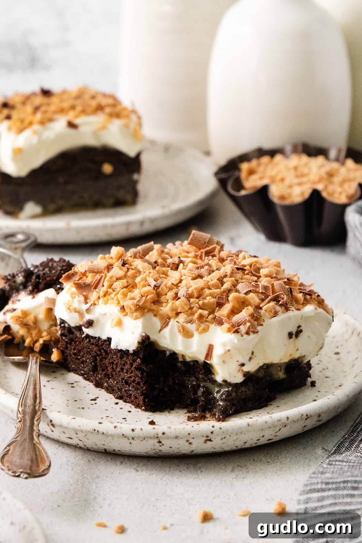 Ultimate Indulgence Cake 2 A perfectly plated slice of decadent Better Than Sex Chocolate Cake, revealing its moist interior, gooey caramel layers, and generous topping of cream cheese frosting and crunchy toffee bits.