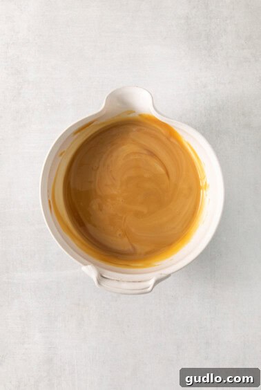 Ultimate Indulgence Cake 13 Luscious caramel sauce being mixed in a bowl, ready to infuse the cake.