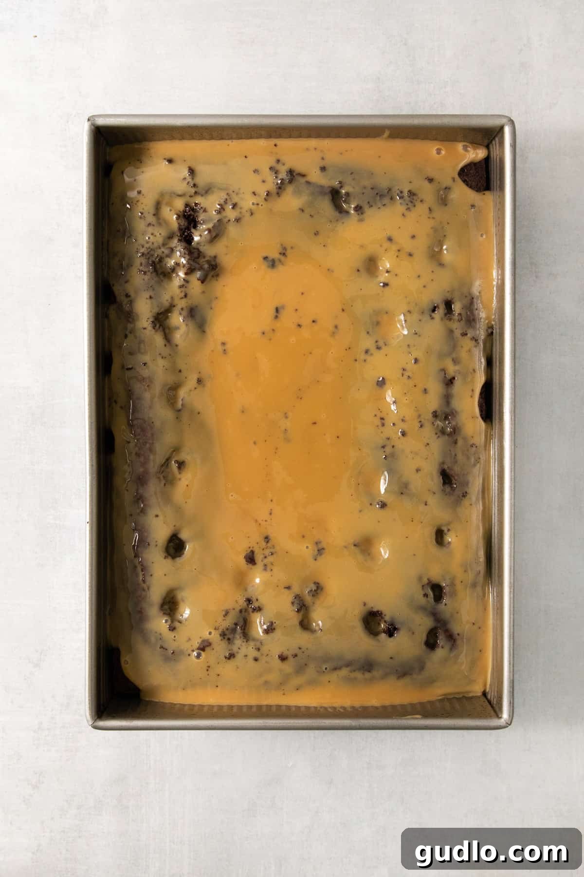 Ultimate Indulgence Cake 3 A rich chocolate cake, freshly baked, sits invitingly in a metal 9x13 inch baking pan, ready for the decadent caramel soaking and frosting layers.
