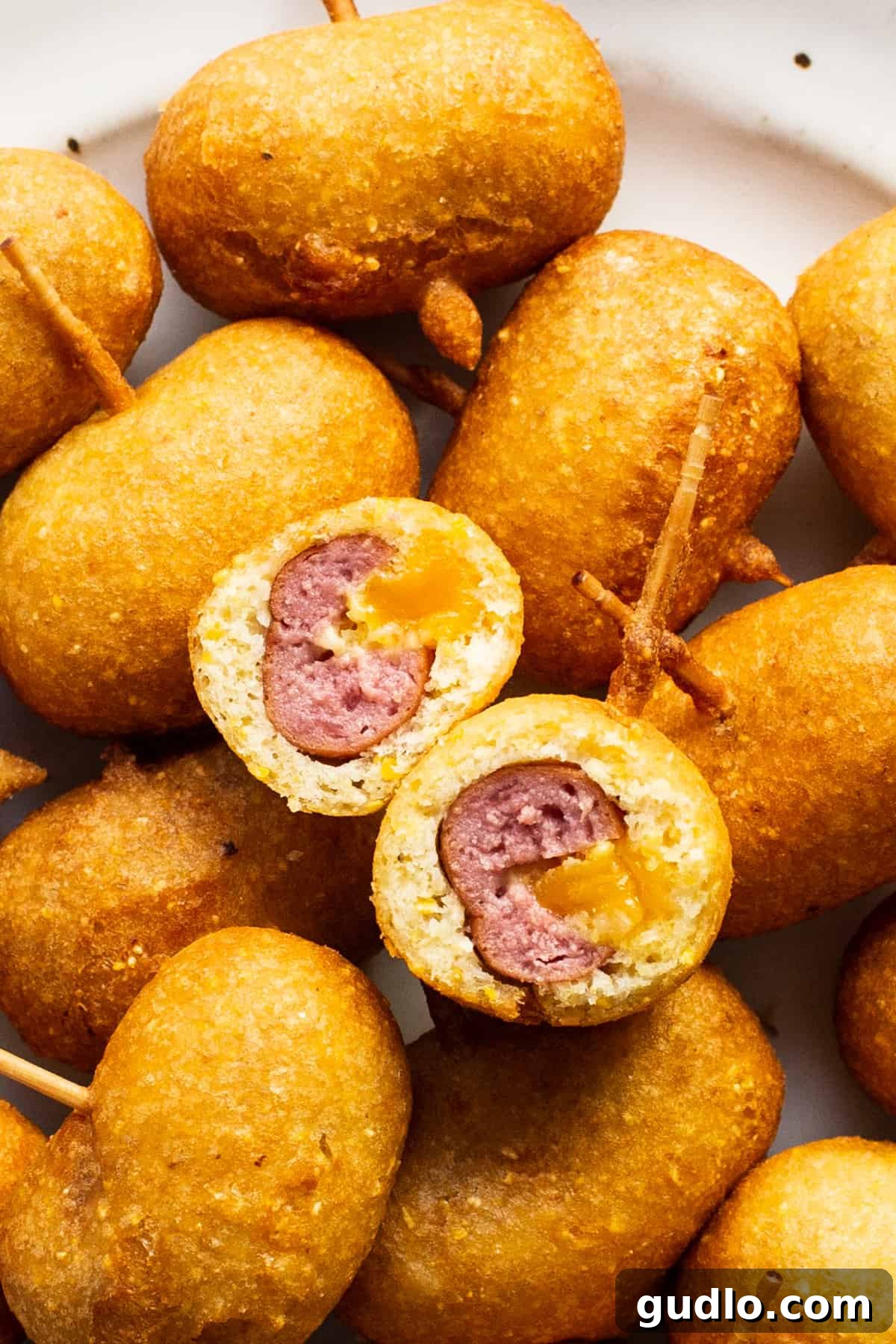 Golden Homemade Corndog Bites 2 A plate topped with a plate of mini corndogs with ketchup and mustard.