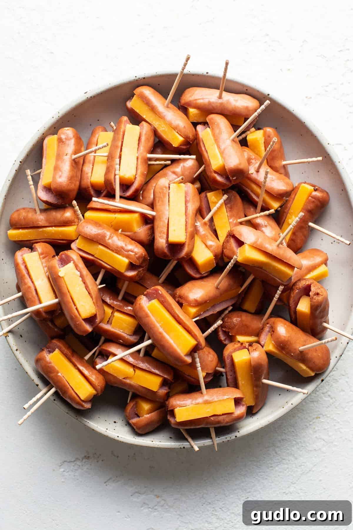 Golden Homemade Corndog Bites 3 Cheesy hot dogs on toothpicks on a plate, ready for frying.