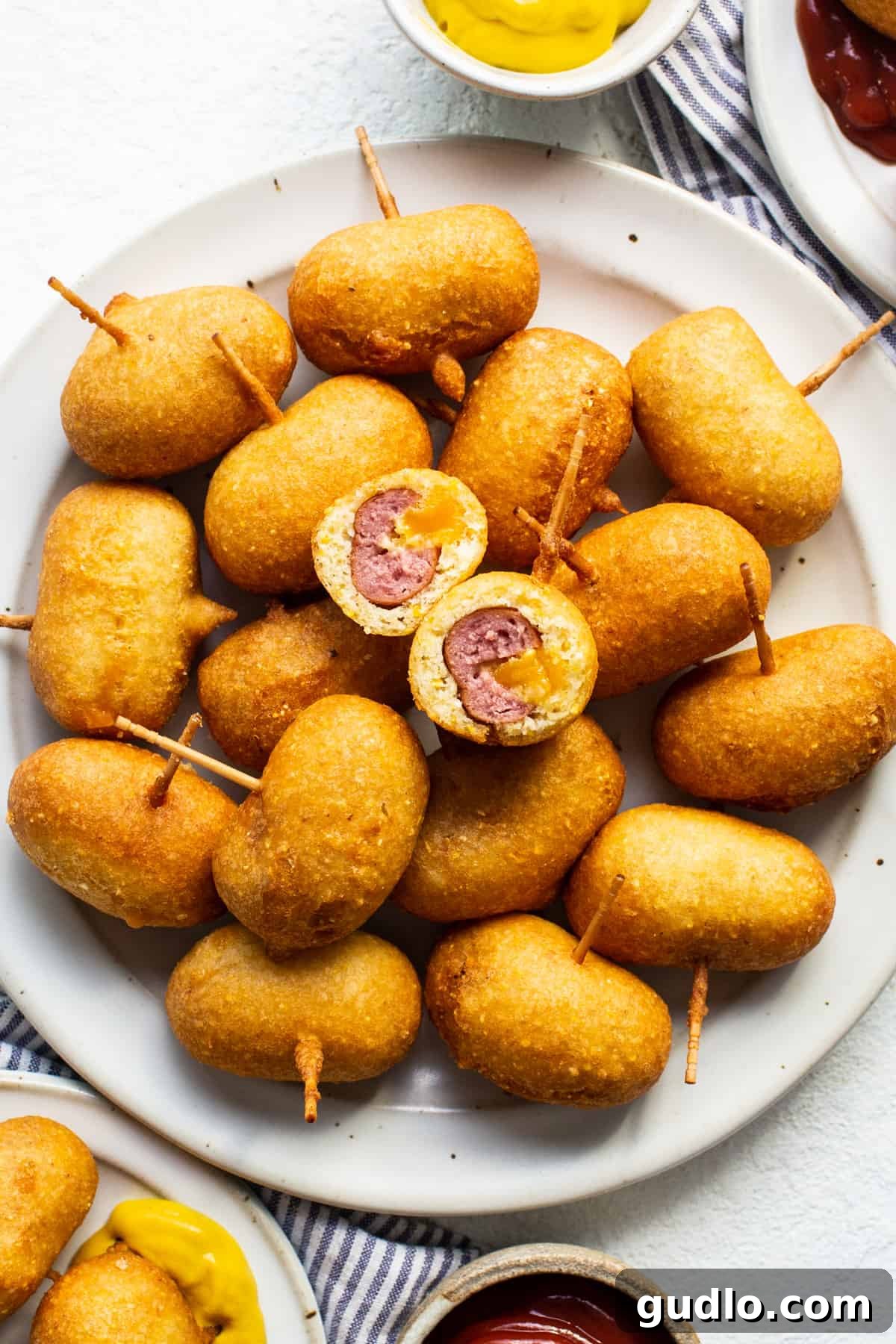 Golden Homemade Corndog Bites 6 A plate of fried mini corndogs with ketchup and mustard dipping sauces.