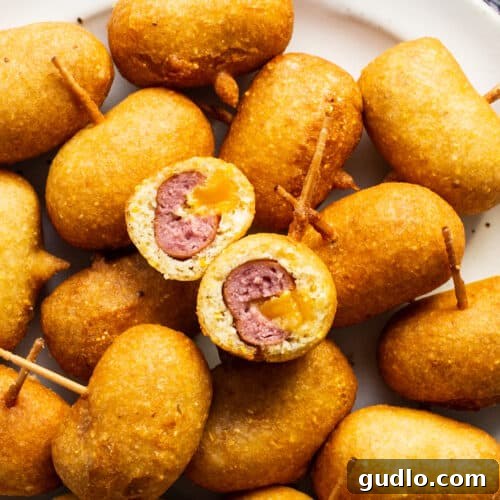 A plate full of fried mini corndogs with toothpicks.