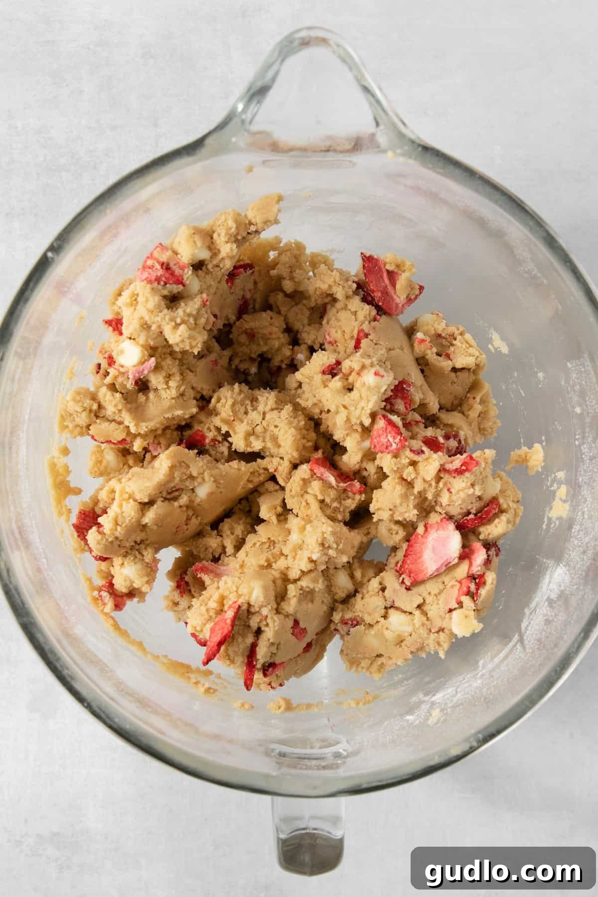 Strawberry cookie dough being prepared in a glass bowl, ready for baking.