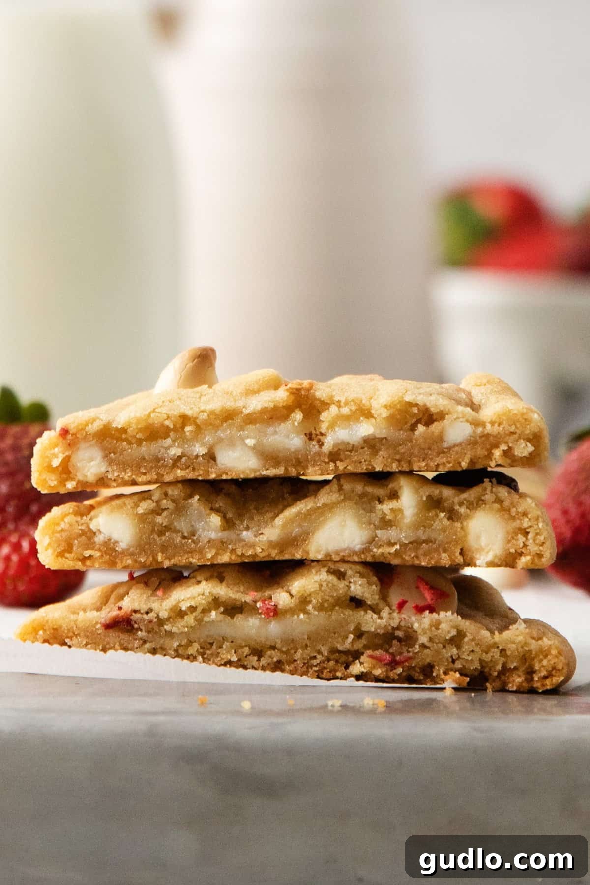 A stack of strawberry cheesecake cookies beside a glass of milk, invitingly presented.