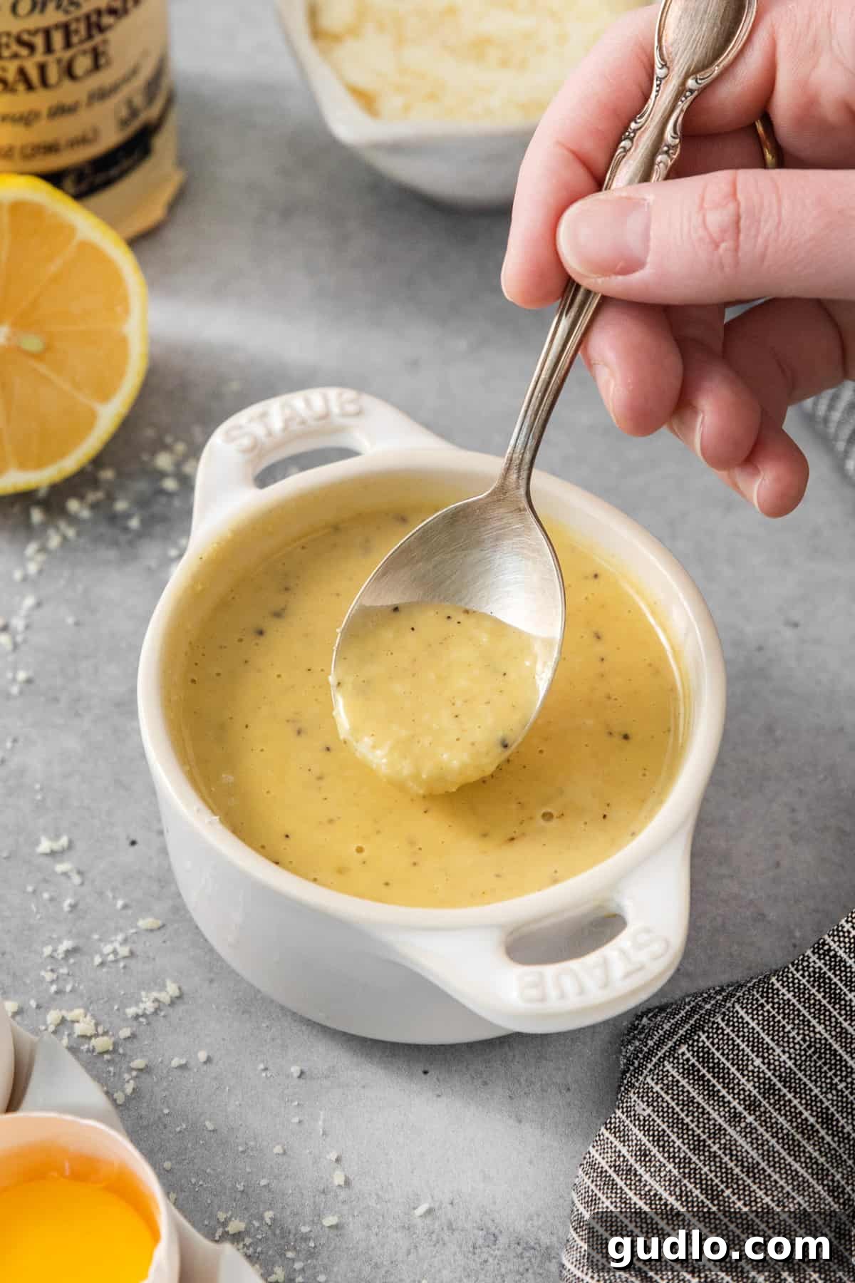 Classic Caesar Dressing 5 A person is slowly pouring olive oil into a bowl while whisking vigorously to create a creamy emulsion.