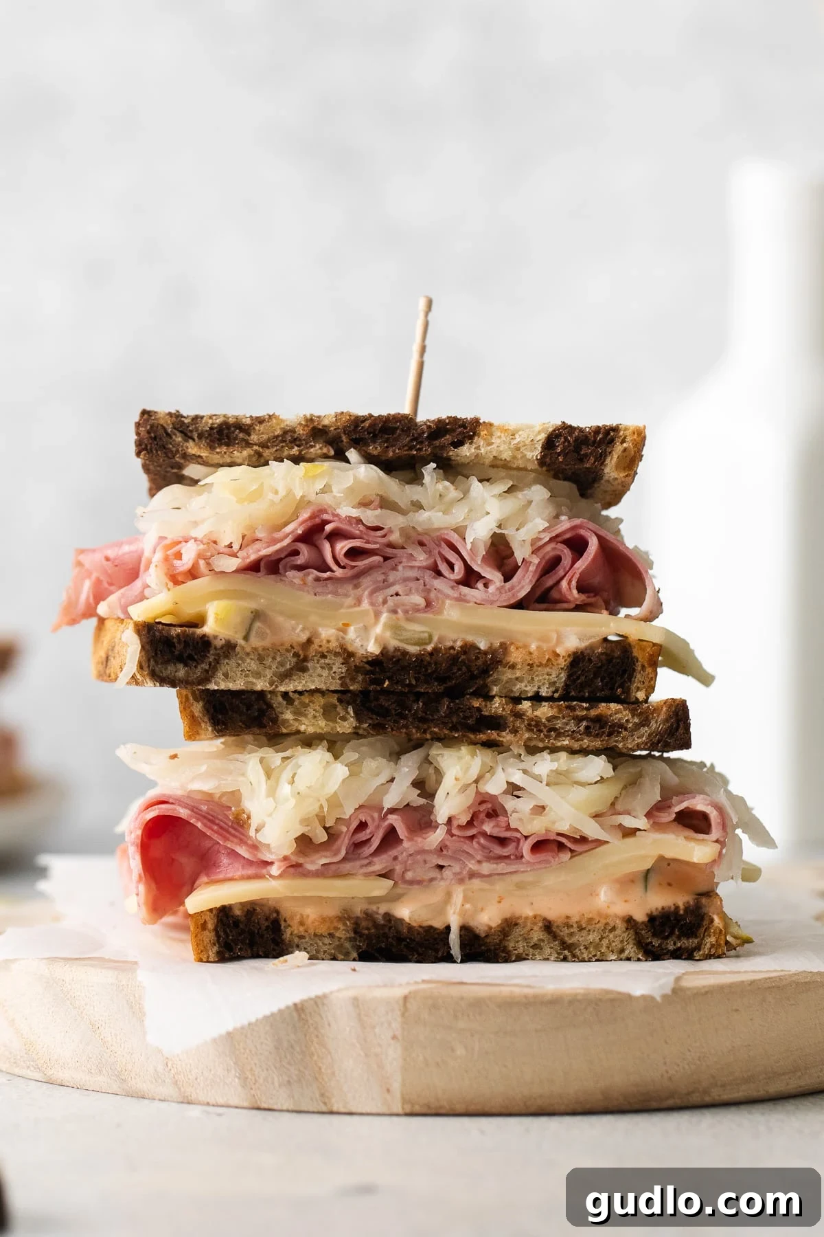A close-up of a partially assembled Reuben sandwich, showing the layers of ingredients before the top slice of bread is added.