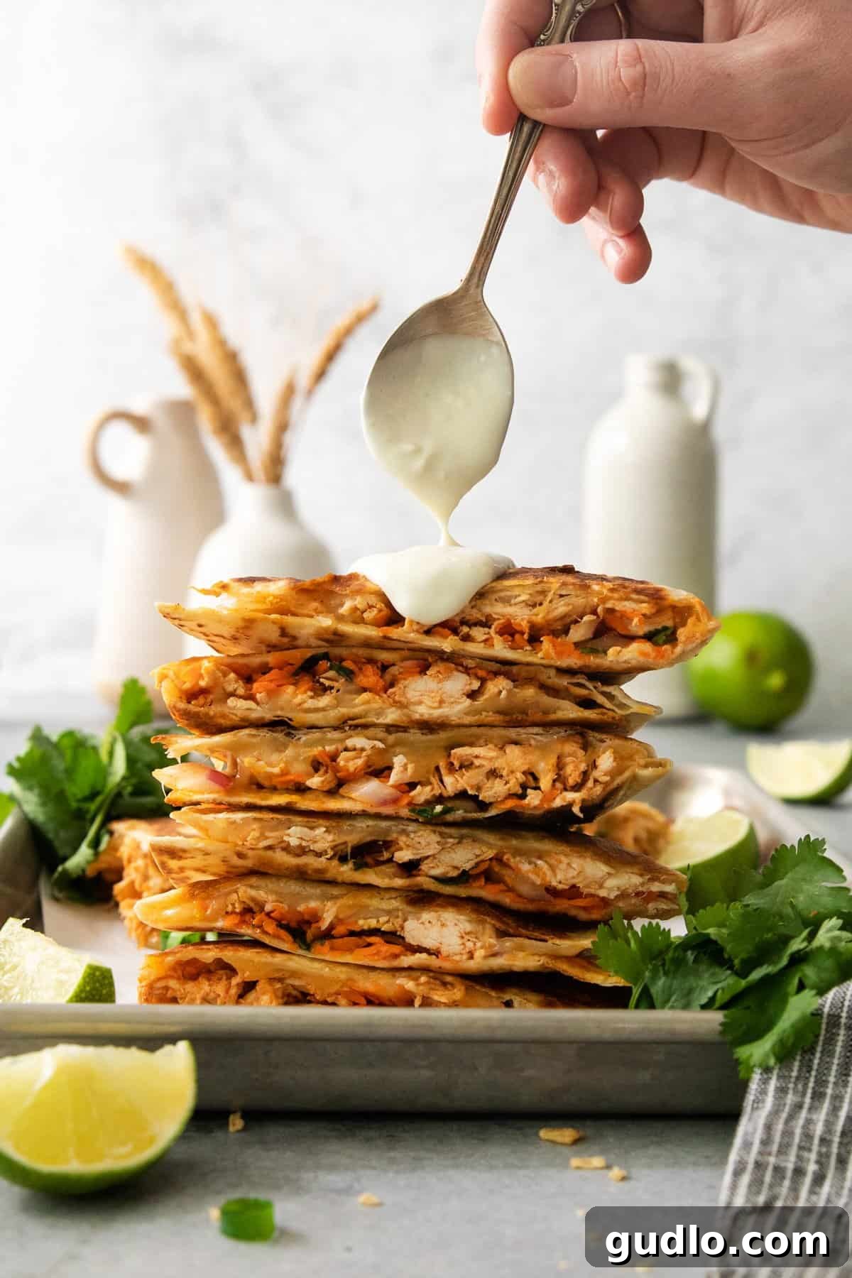 A stack of chicken quesadillas on a plate with a scoop of guacamole, ready to be enjoyed.