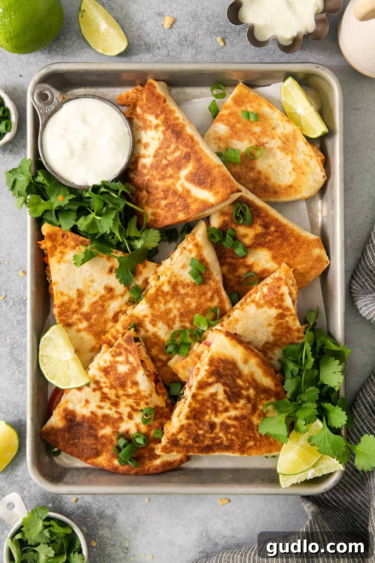 Freshly prepared chicken quesadillas arranged on a tray with vibrant lime wedges.