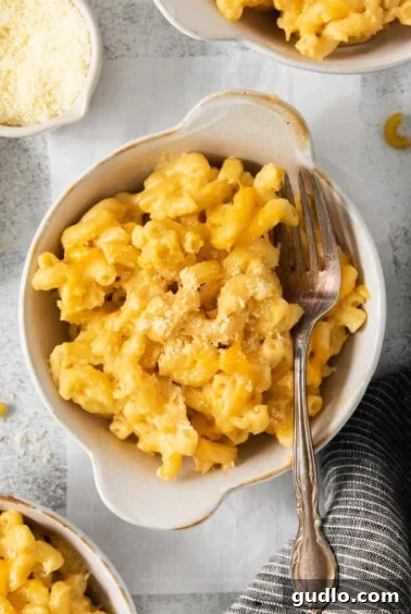 Macaroni and cheese in a bowl with a fork, steaming and ready to eat.
