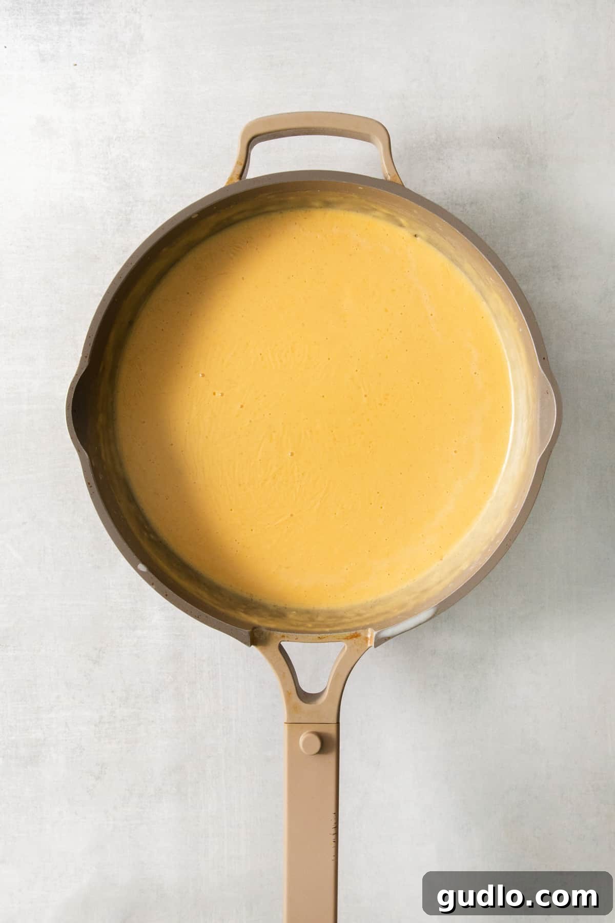 The Ultimate Chick-Fil-A Mac and Cheese Clone 4 A frying pan filled with a vibrant yellow cheese sauce, ready to be combined with pasta.