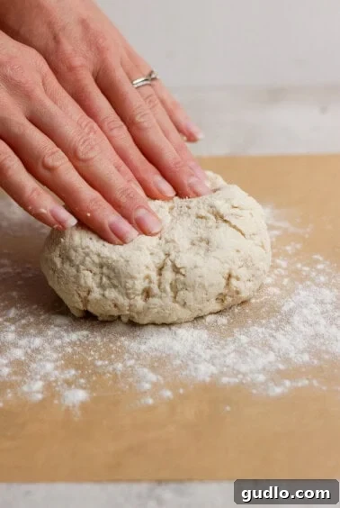 Protein Packed Pepperoni Pizza Bites 14 Two hands pressing down on a ball of dough on a floured surface, preparing to knead or shape it.