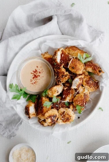 A plate with golden-brown chicken nuggets and a small bowl of dipping sauce.