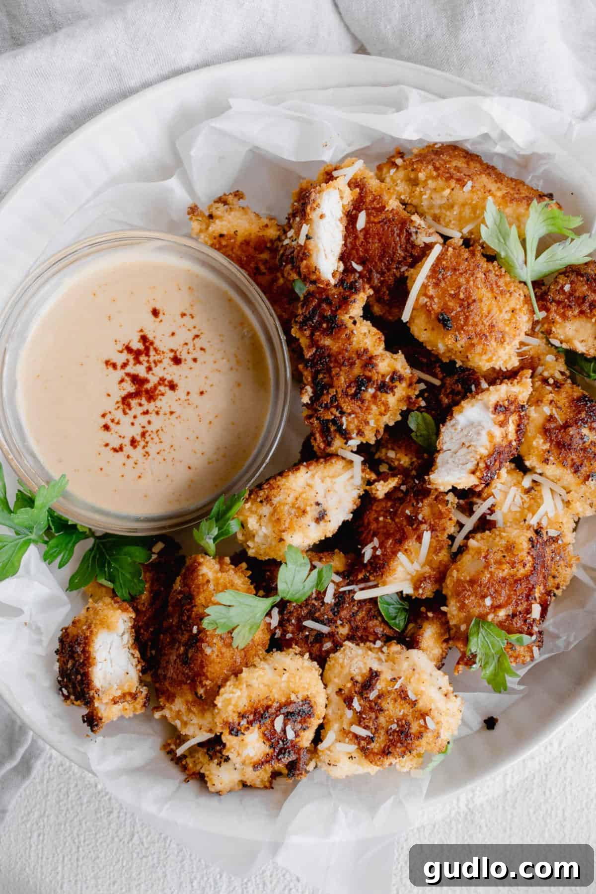Perfectly golden chicken nuggets served with an array of sauces. A vibrant plate of crispy Parmesan chicken nuggets accompanied by various dipping sauces, garnished with fresh parsley.
