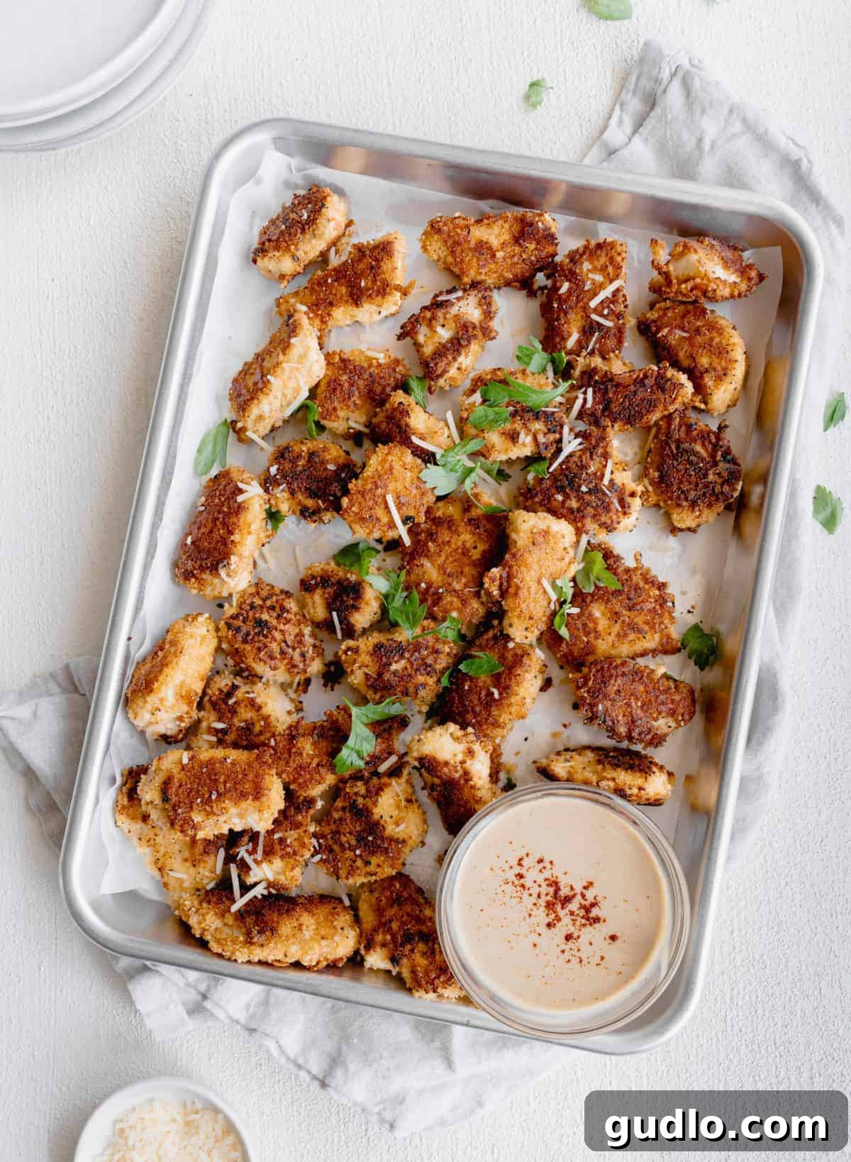 Chicken nuggets sizzling to perfection in a pan. Golden-brown Parmesan chicken nuggets cooking in a hot skillet, with some already cooked and ready.