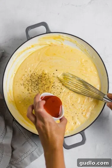 adding hot sauce to mac and cheese sauce.