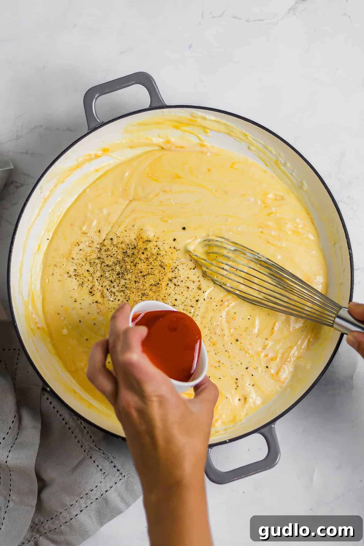 Say hello to the BEST mac and cheese on the internet! This Classic Mac and Cheese recipe is cheesy, creamy and made completely on the stovetop. Enjoy! Hot sauce being drizzled into the creamy mac and cheese sauce, then expertly whisked in to perfectly blend the flavors.