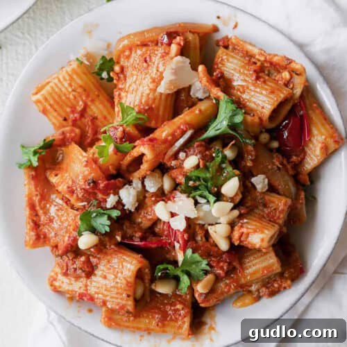 A plate of sun dried tomato pasta garnished with parsley.