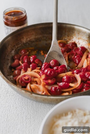 A pan-fried dish showcasing rice and a flavorful cherry sauce, perfect with sun-dried tomato pasta.