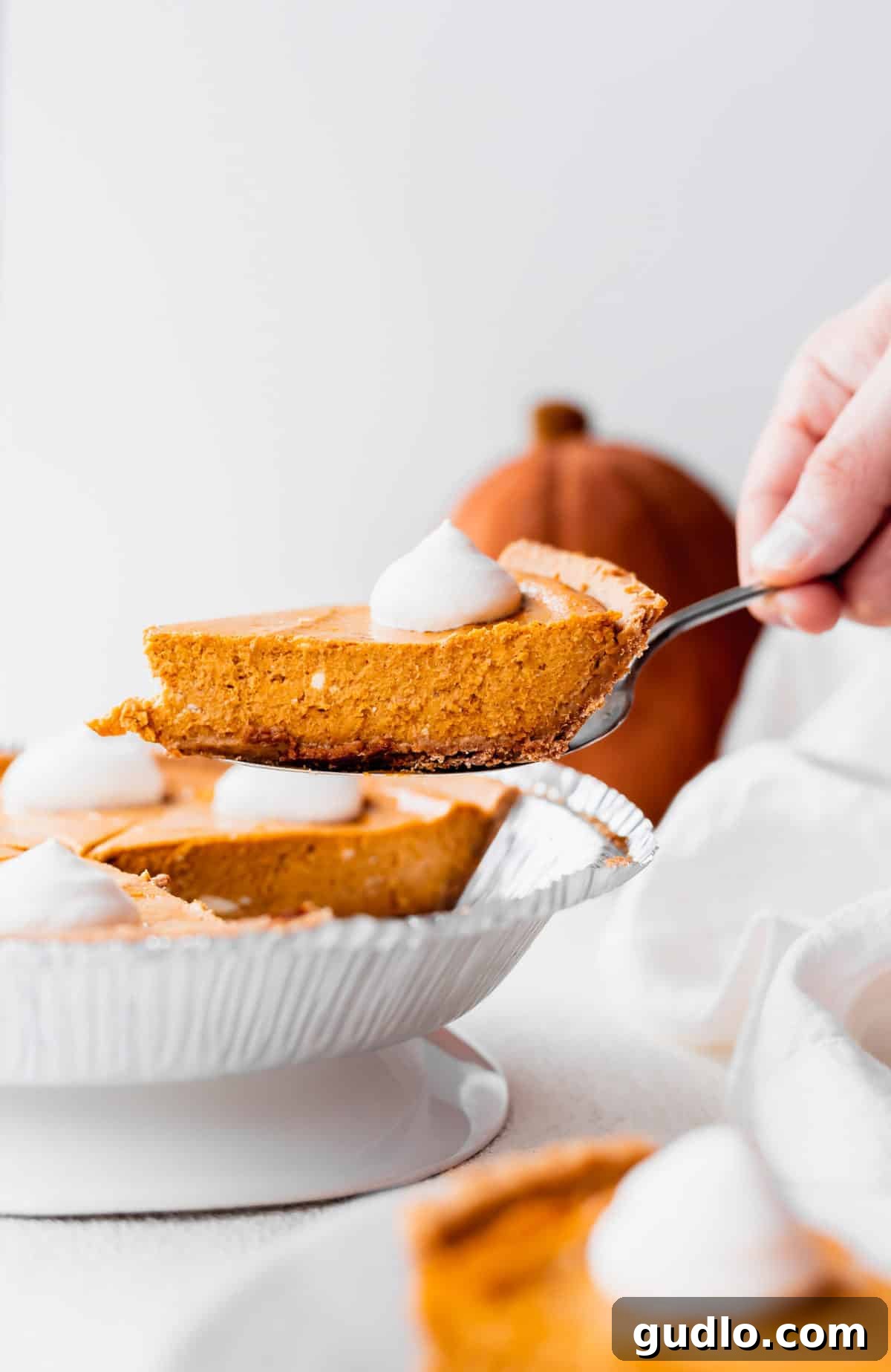 Effortless Pumpkin Cheesecake 7 A warm, inviting scene showing a perfect slice of pumpkin cheesecake being carefully served onto a pristine white plate, ready for immediate enjoyment.