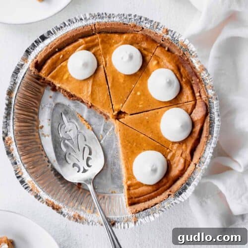 Effortless Pumpkin Cheesecake 8 A beautifully presented pumpkin cheesecake with a slice removed, showcasing its creamy texture and golden crust, ready to be enjoyed.