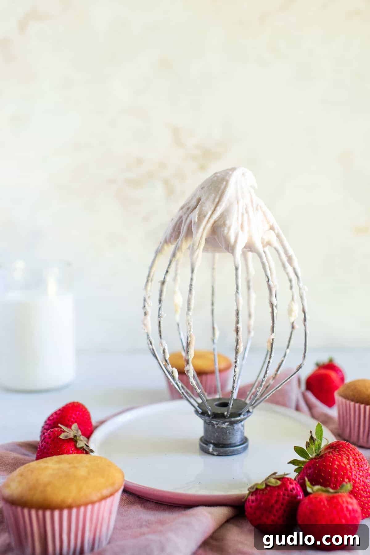 Strawberry Cream Cheese Frosting on a whisk. Close-up of fluffy strawberry cream cheese frosting on a whisk, ready for application.