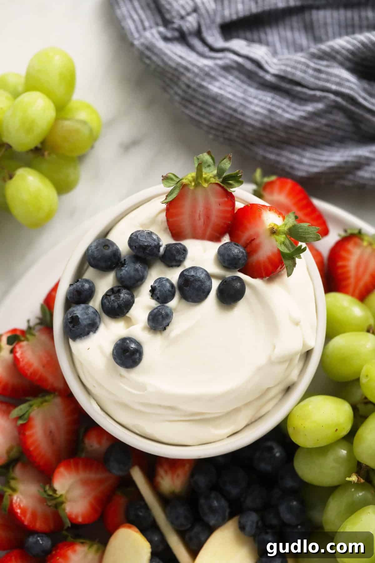 cream cheese fruit dip in a bowl surrounded by fresh fruit.