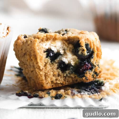 An unwrapped blueberry cream cheese muffin, revealing its moist interior and the creamy, delightful filling.